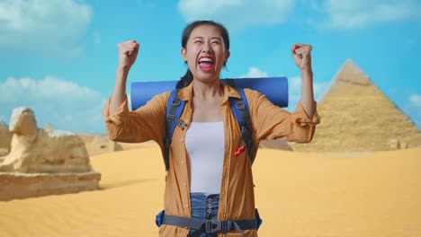 asian female hiker with mountaineering backpack screaming goal celebrating the success while traveling in pyramid of giza