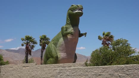 a giant artifical dinosaur looms over visitors as a roadside attraction in the mojave desert near cabazon california