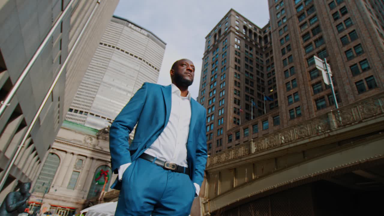 New York, USA, 15 aprile 2026: Ampia inquadratura dal basso di un uomo d'affari in piedi a Midtown Manhattan. Prospettiva grandangolare di un uomo in abito blu in piedi fuori dall'area del Grand Central Terminal a New York