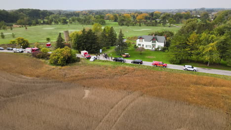 car traffic accident incident site at countryside road, first aid vehicles fire trucks and stationary cars along the street roadside, green fields and agricultural lands around, aerial view