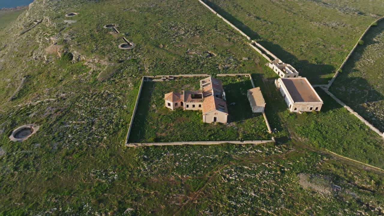 ángulo alto de vista de pájaro orbita alrededor de un viejo edificio militar abandonado en menorca, españa