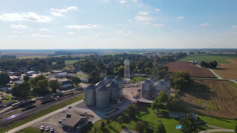 drone flying towards revealing a water tower and many silos made of steel in a farm of trenton, kentucky
