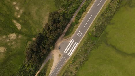 toma aérea de arriba hacia abajo pista de aterrizaje de emergencia en camino rural en uruguay durante el día soleado rodeado de bosque verde