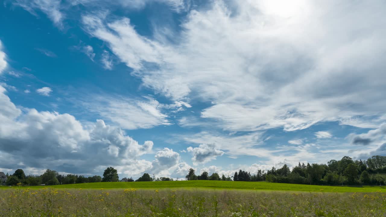 nubes blancas esponjosas flotan a través del cielo por encima de las laderas cubiertas de hierba y el prado