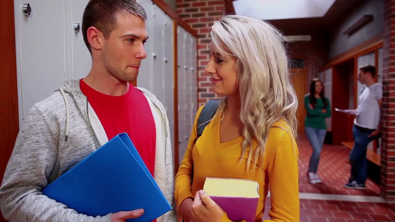 dos estudiantes coqueteando en el pasillo