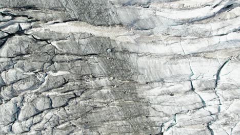 bovenaanzicht van ijsgletsjer in de bergen met diepzwarte spleten en spleet, smeltende gletsjer in zwitserland als gevolg van de opwarming van de aarde