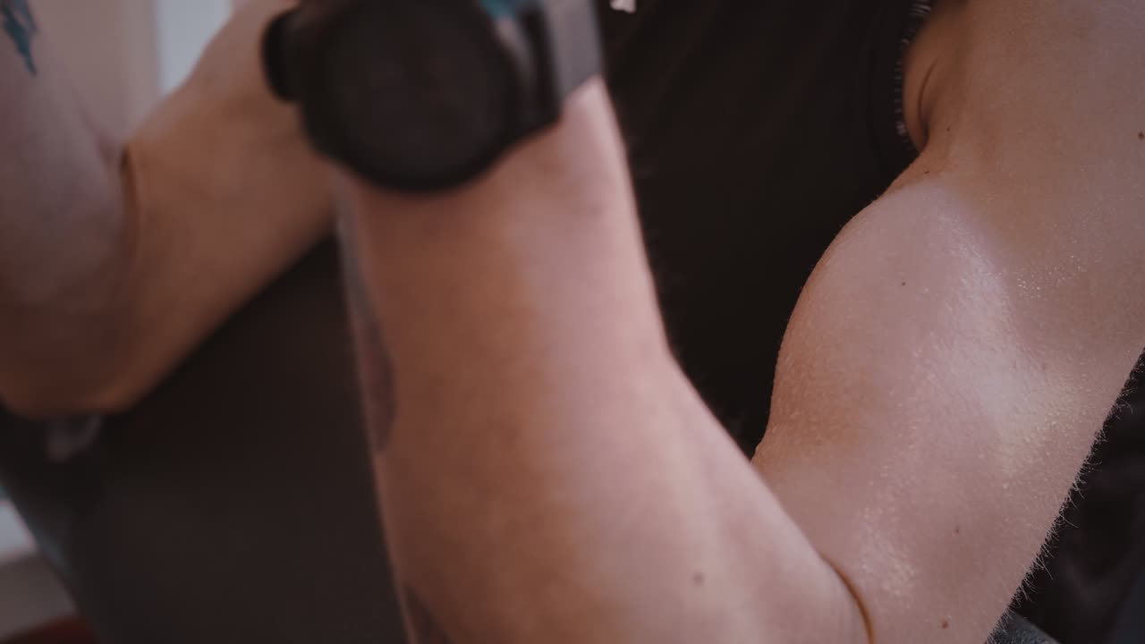las gotas de sudor cubren el brazo musculoso haciendo curl de araña bicep en el gimnasio, primer plano