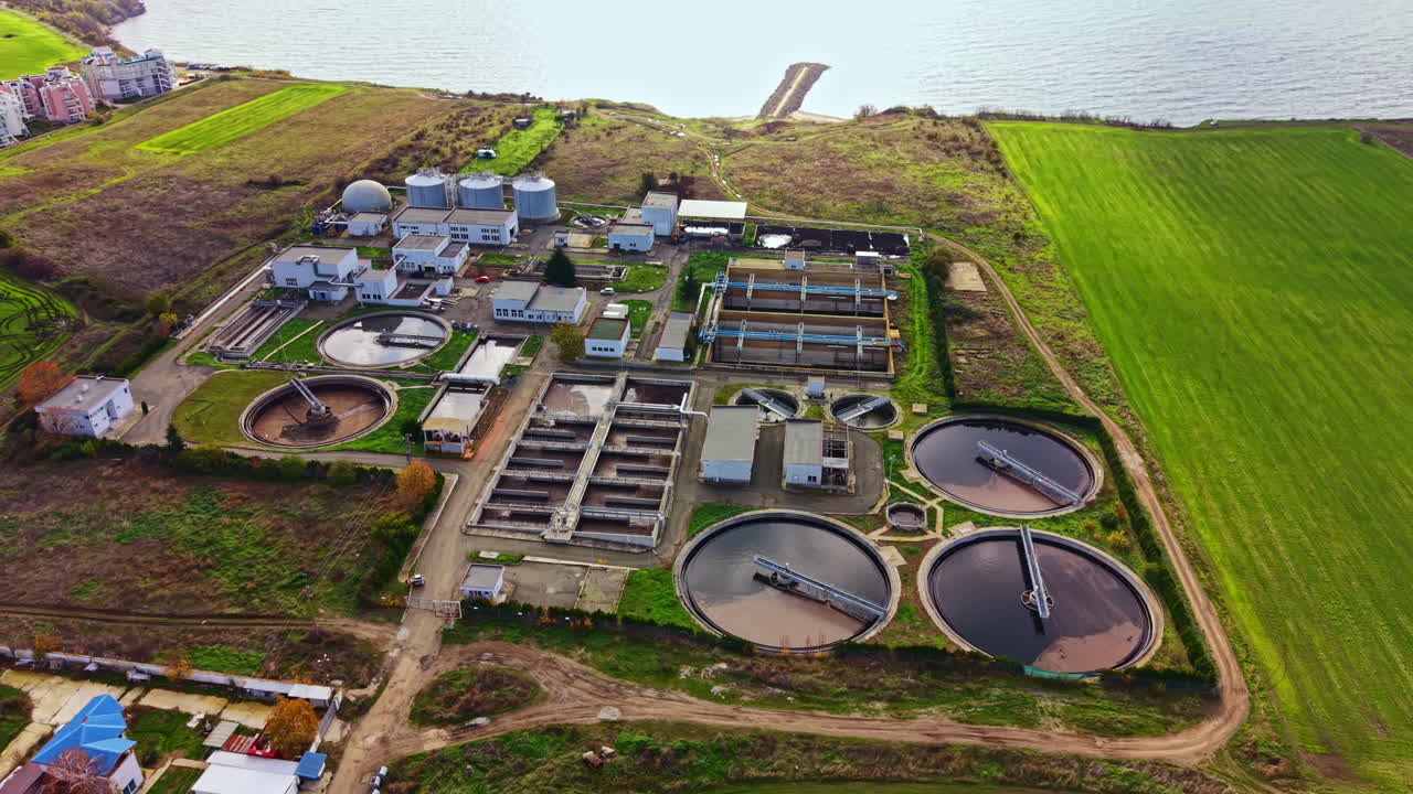 Wastewater treatment facility nestled between land and sea under a clear blue sky