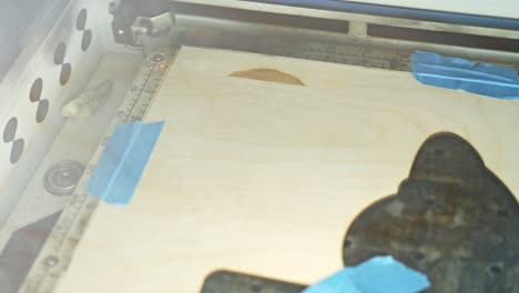 a laser engraver etching a design into wood in a workshop