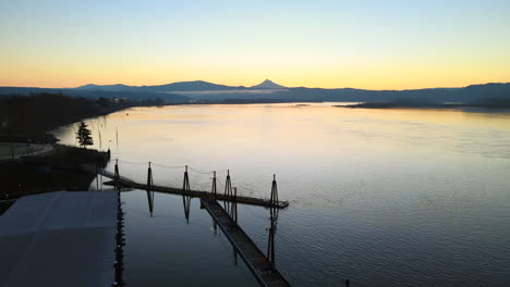 drone volando sobre un impresionante lago y muelle, paisaje perfecto durante un amanecer, rodeado de montañas en la distancia