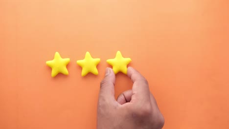 hand placing a star rating on an orange background