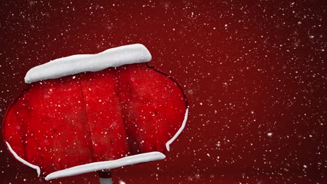 Snow-falling-over-snow-covered-red-sign-post-against-red-background