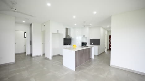 modern white open plan kitchen with stone tip island bench, gas cooktop and stainless steel appliances