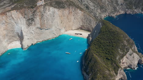 Bird's-Eye-View-Of-Shipwreck-On-A-Beach-Between-Towering-Cliffs