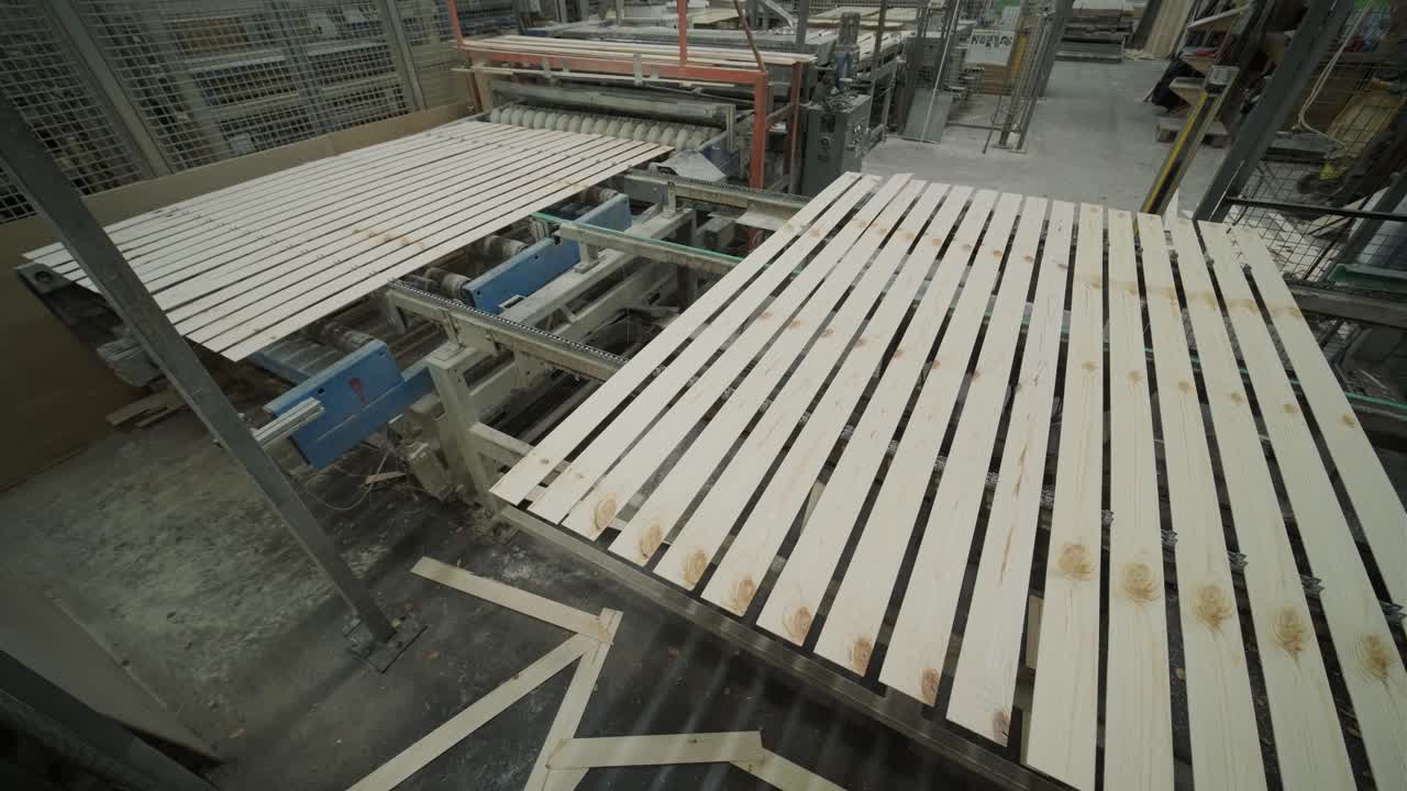 Assi di legno che si muovono su un nastro trasportatore automatizzato in fabbrica.