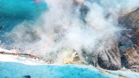 picking up ocean trash underwater causing the sand to be stirred up near the camera