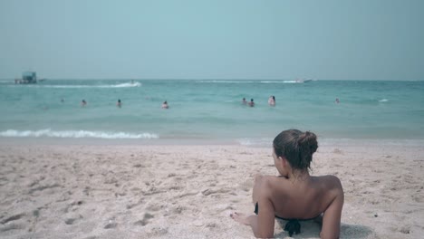 girl-looks-at-swimming-people-sailing-motorboat-on-horizon