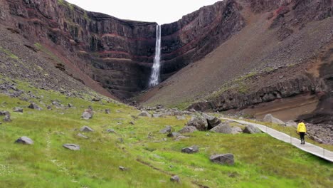 mujer caminando hacia una cascada en islandia