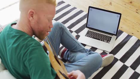hombre albino afroamericano con rastas tocando la guitarra y cantando