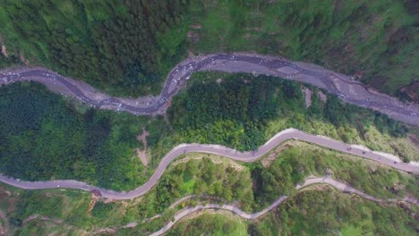 aerial view of a curved winding roads trough the forest with river, beautiful nature and transportation from panoramic view, cars are going through the road on the mountain with green forest