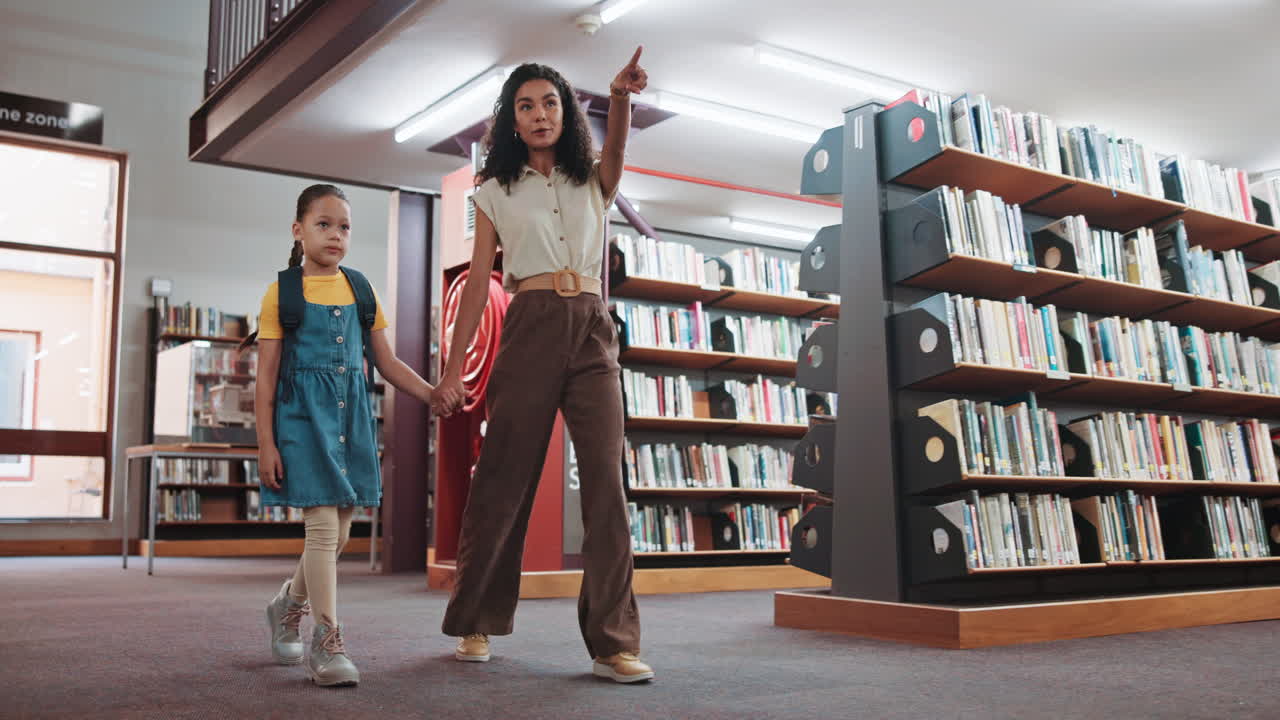 Donna e bambina felici che camminano mano nella mano in biblioteca