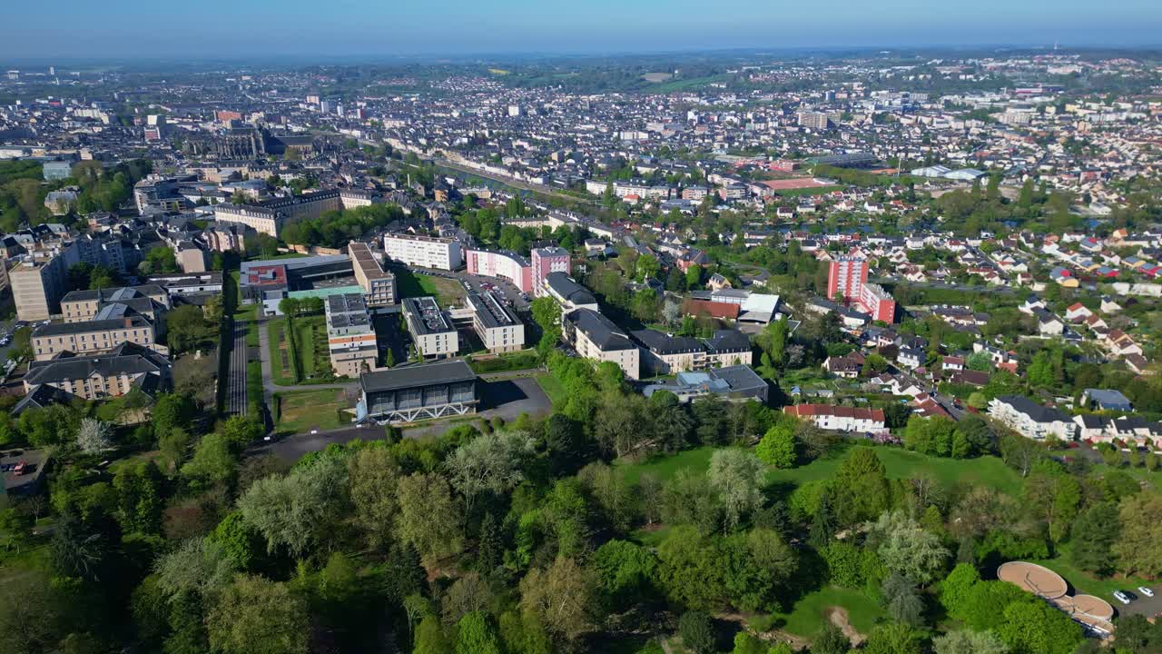 Panorama view of a Le Mans city with apartment buildings and green tree-covered urban Banjan Park with local cathedral in the background at Les Maillets district, France. Aerial drone sideways
