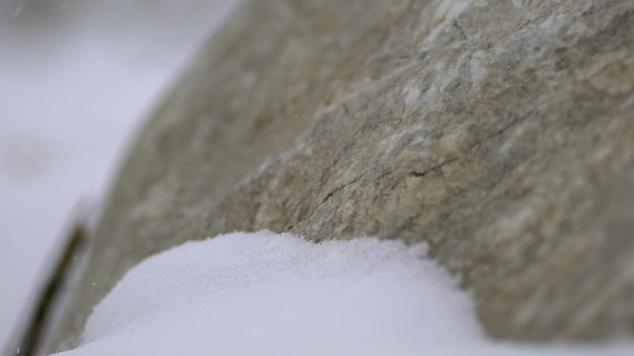 Neve leggera che cade su una grande pietra in inverno