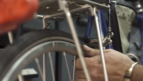 a bicycle mechanic tightening the screw that holds the rear brake cable