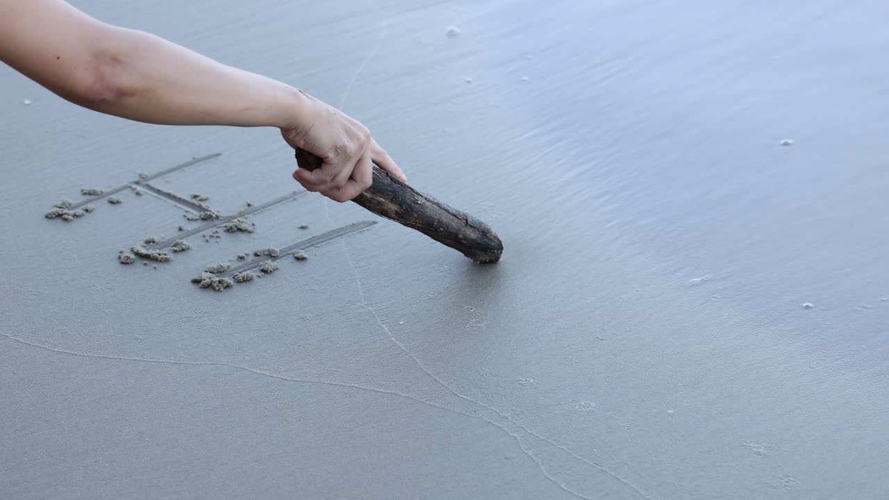 Sequential writing of the word 'Hi' on sand.