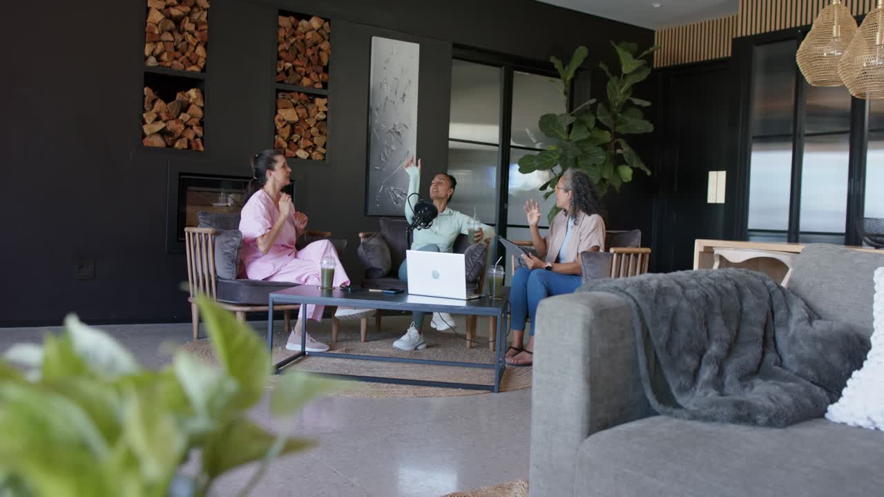 Microphone starting recording, three hosts speaking, gesturing and referencing laptop for podcast