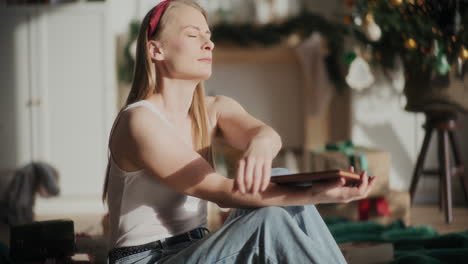 mujer con los ojos cerrados sosteniendo un libro en un hogar brillante durante la navidad