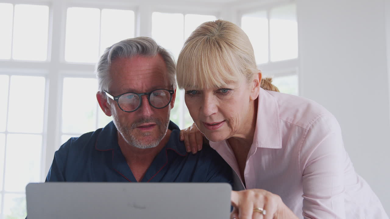 Senior Couple With Man In Wheelchair Looking Up Information About Medication Online Using Laptop