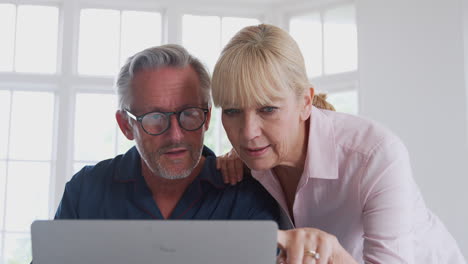 senior couple with man in wheelchair looking up information about medication online using laptop