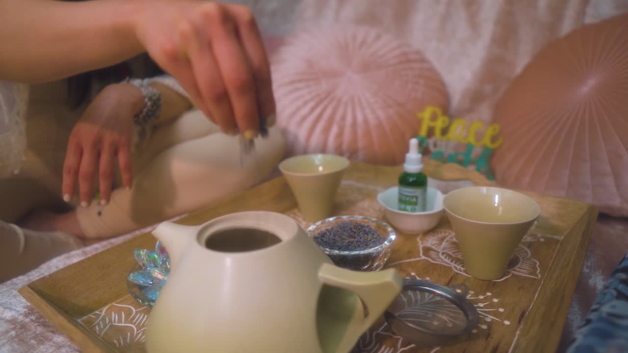 Spiritual healer is putting herbs into the tea pot to heal her client with the natural ingridenece in peaceful environment