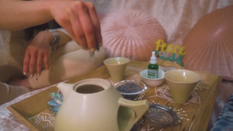 spiritual healer is putting herbs into the tea pot to heal her client with the natural ingridenece in peaceful environment