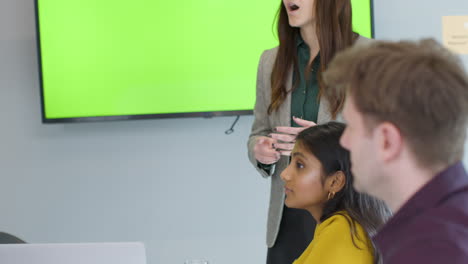 mujer de negocios dando una presentación a sus colegas con tv de pantalla verde
