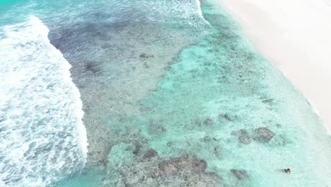 aerial above waves blue sea ocean water crashing in to white sand tropical beach paradise