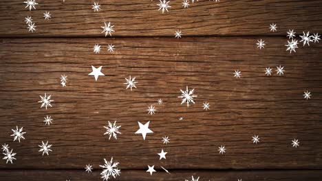 Animation-of-christmas-stars-falling-over-wooden-background