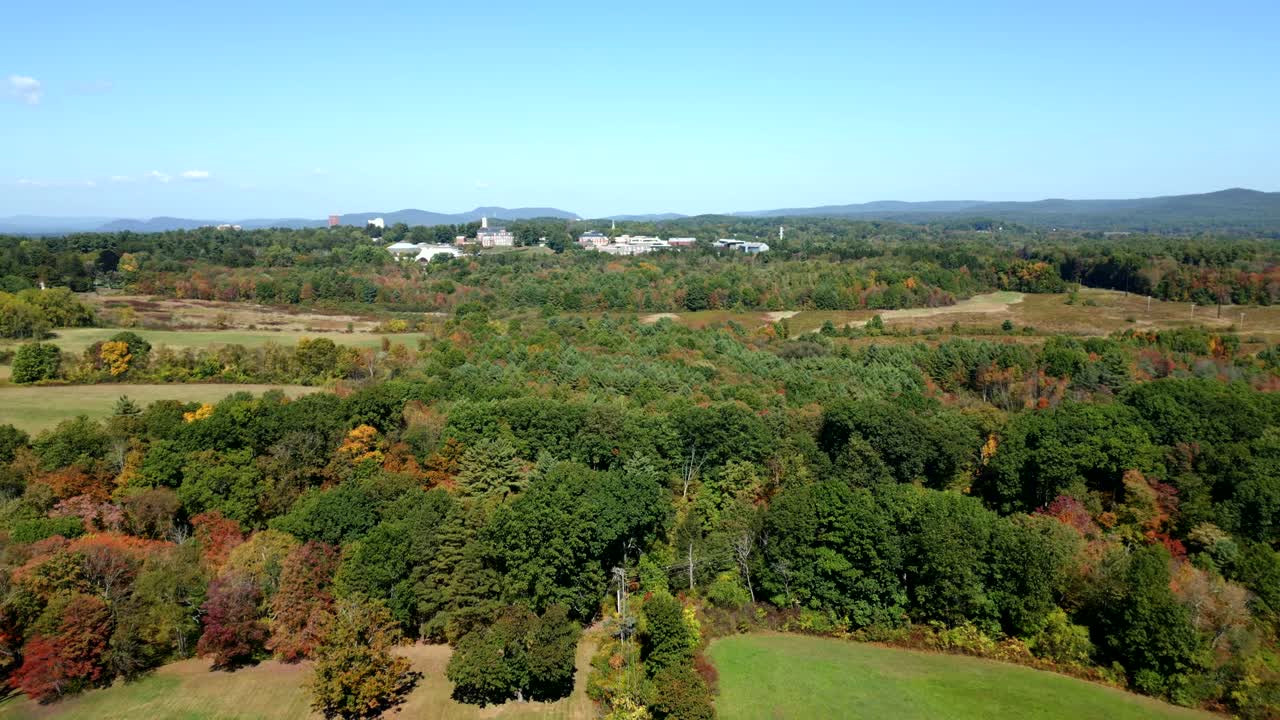 Expansive drone view of colorful autumn forest with distant Amherst College in background, Amherst, Massachusetts, USA