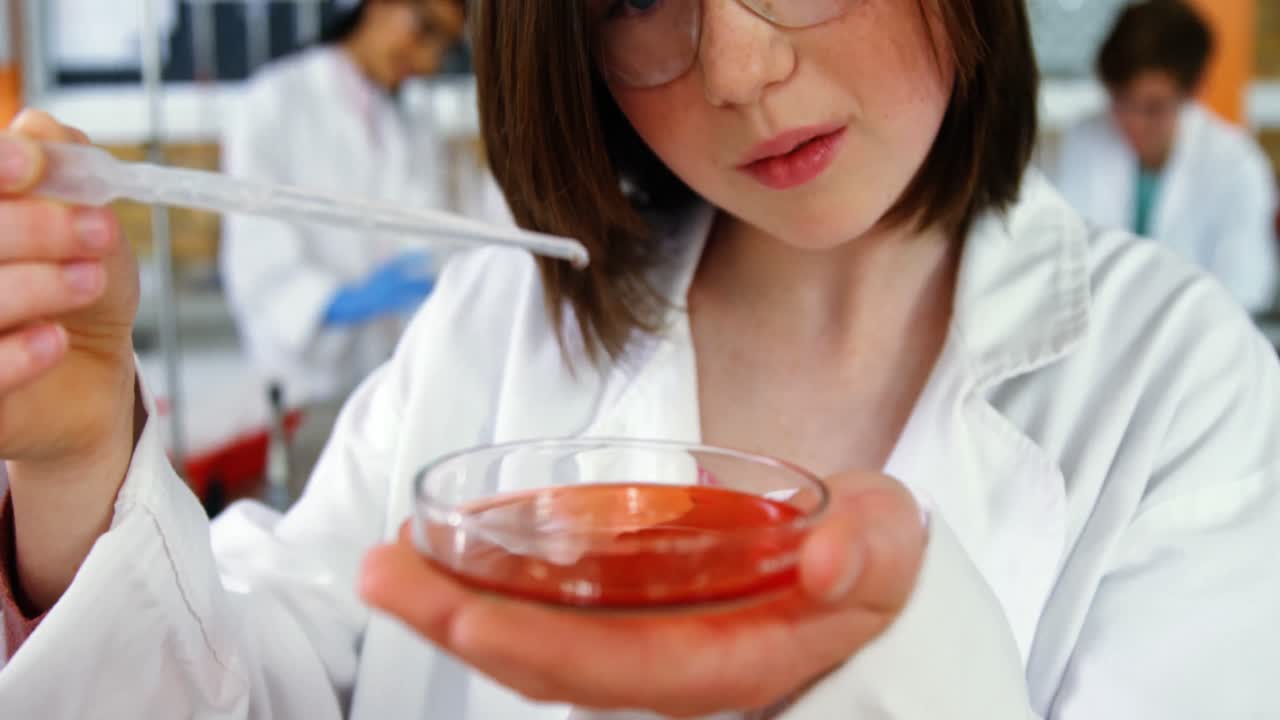 niña de escuela experimentando con productos químicos en el laboratorio de la escuela