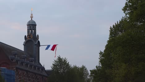 Dutch-flag-and-vane-hanging-on-Academy-Building-of-Leiden-University-on-national-holiday-King's-Day-in-the-Netherlands