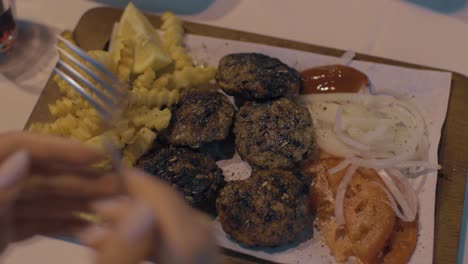 woman eating meat patties with potatoes and vegetables