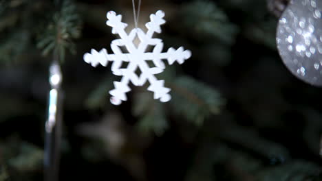 snowflake toy hanging and waving on christmas tree branch close-up