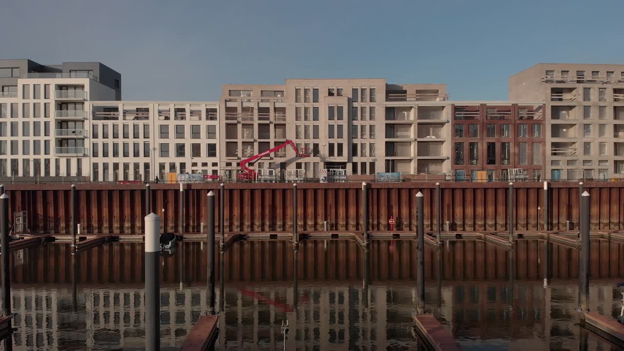 Exterior facades of residential building under construction in the Noorderhaven neighbourhood and recreational port in the foreground reflecting in the water in the foreground