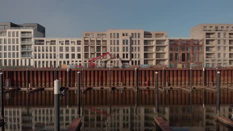 exterior facades of residential building under construction in the noorderhaven neighbourhood and recreational port in the foreground reflecting in the water in the foreground