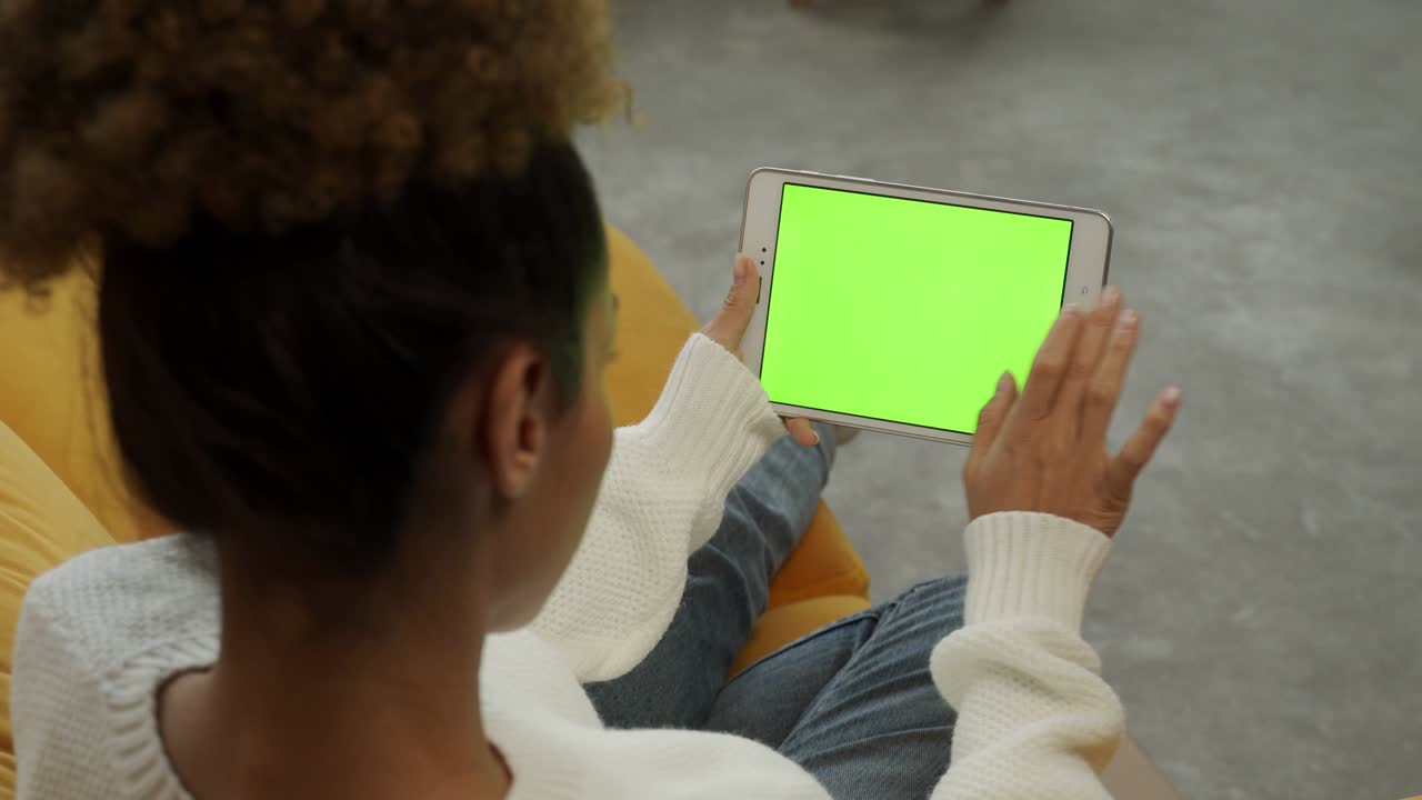 donna afroamericana, usa un dispositivo tablet con un chromakey mentre è seduta sul divano