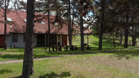 mesas de picnic vacías bajo los árboles cerca de un edificio turístico