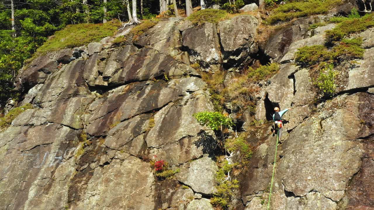 imágenes aéreas orbitan alrededor de un escalador solitario en un acantilado en maine revelando cielos azules