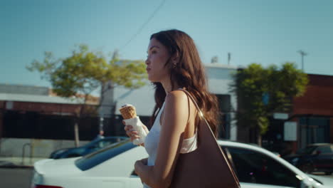 attractive girl tasting ice cream going down street. asian woman licking dessert