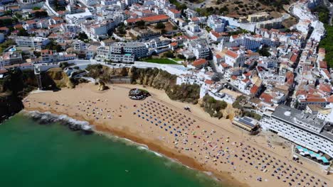 drone shot tilting up from the beach to the town, in albufeira